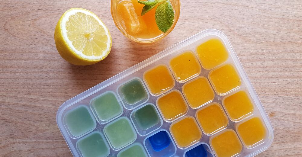 Eiswürfelbehälter mit gefrorenen Würfeln aus Zitronen- und Limettensaft