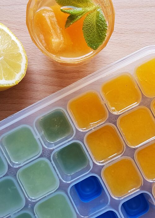 Eiswürfelbehälter mit gefrorenen Würfeln aus Zitronen- und Limettensaft